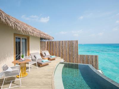 Terrasse mit Pool und Liegestühlen direkt über dem türkisfarbenen Meer bei klarem Himmel.