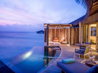 Luxuriöse Überwasserbungalows mit Infinity-Pool und Meerblick bei Sonnenuntergang.