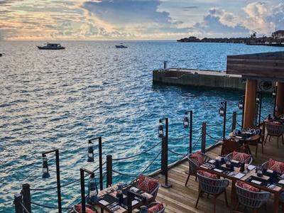 Meerblick von einem Hotelterrassenrestaurant mit gedeckten Tischen und Booten auf dem Wasser.