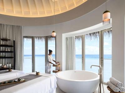 Modernes Hotelzimmer mit Panoramafenstern und Meerblick, heller Raum mit Badewanne und Liegen.