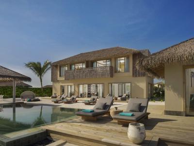 Moderne Villa mit Pool, Sonnenliegen und Palmen unter klarem Himmel für Urlaub und Erholung.