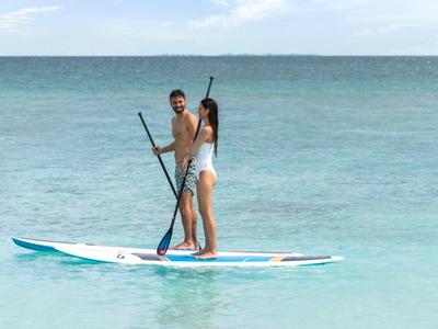 Zwei Personen stehen auf einem Paddleboard im klaren blauen Wasser.