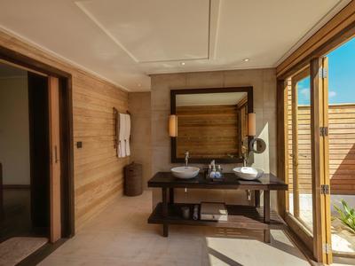 Helles Badezimmer mit Holzverkleidung, Doppelwaschbecken und großen Fenstern zum Außenbereich.