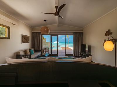 Modernes Wohnzimmer mit Sofa, Deckenventilator und Blick auf den Ozean durch große Fenster