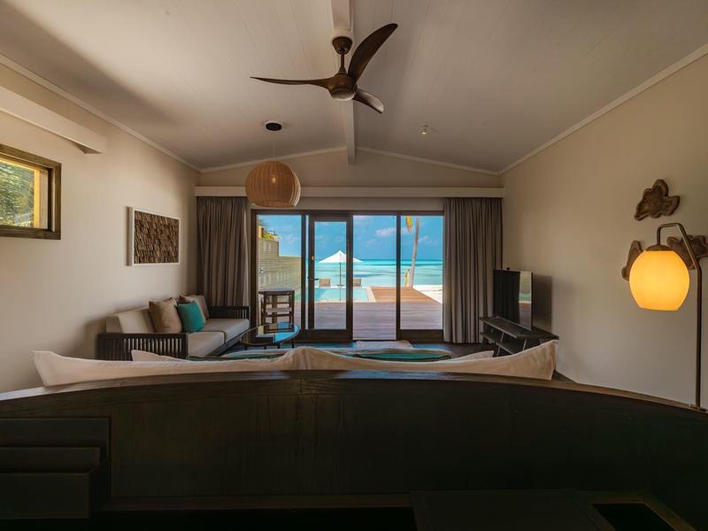 Modernes Wohnzimmer mit Sofa, Deckenventilator und Blick auf den Ozean durch große Fenster