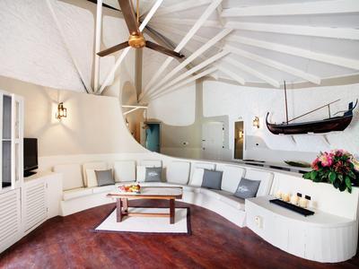 Soggiorno moderno con divano in pelle bianca, pavimento in legno e decorazioni nautiche.