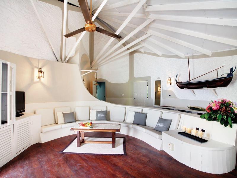 Heller Raum mit weißem Rundsofa, Deckenbalken, Holzdecke, hölzernem Boden und Wikingerschiff-Deko.