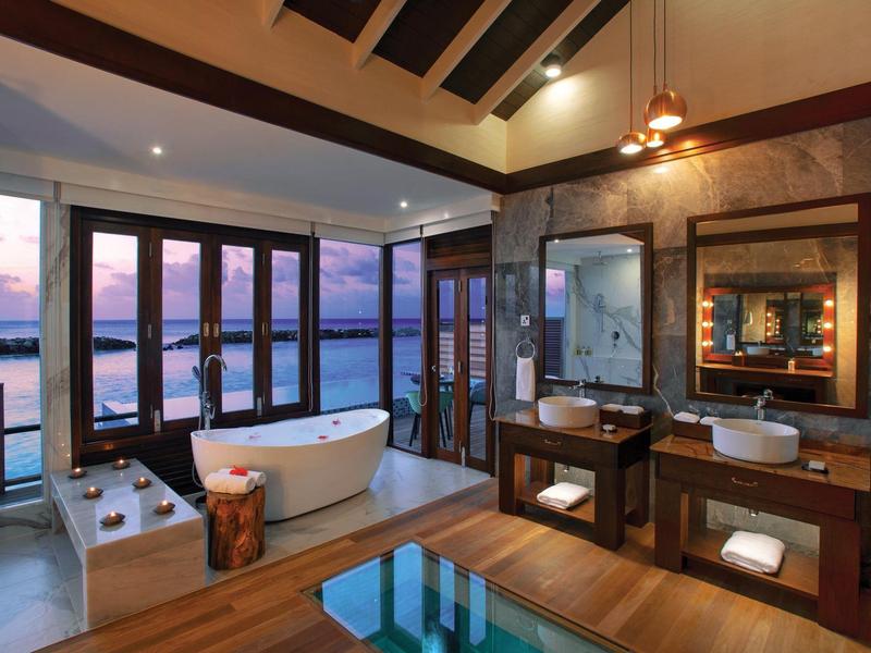 Luxuriöses Badezimmer mit freistehender Badewanne, Holzmöbeln und großer Glasfront mit Meerblick.