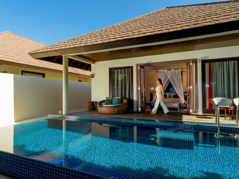 Modernes Haus mit Terrasse und großem blauen Swimmingpool bei sonnigem Wetter.