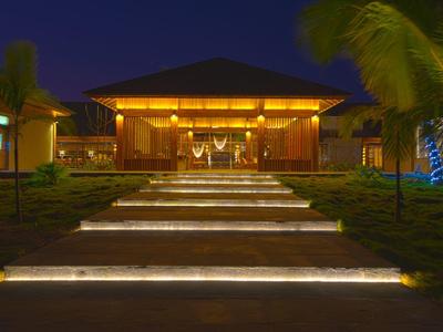 Moderne Villa bei Nacht mit beleuchtetem Weg und Palmen entlang des Eingangsbereichs.
