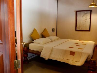 Gemütliches Schlafzimmer mit Doppelbett, gelben Kissen und gerahmtem Bild an der Wand.