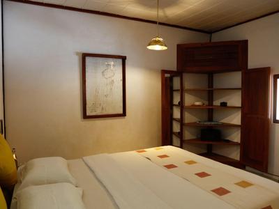 Gemütliches Hotelzimmer mit Doppelbett, Regalen und warmem Licht.