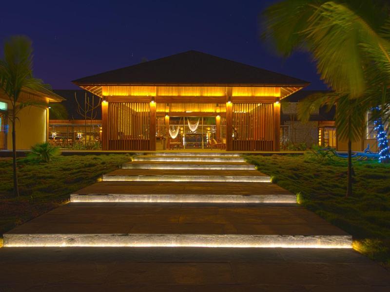 Moderne Villa bei Nacht mit beleuchtetem Weg und Palmen entlang des Eingangsbereichs.