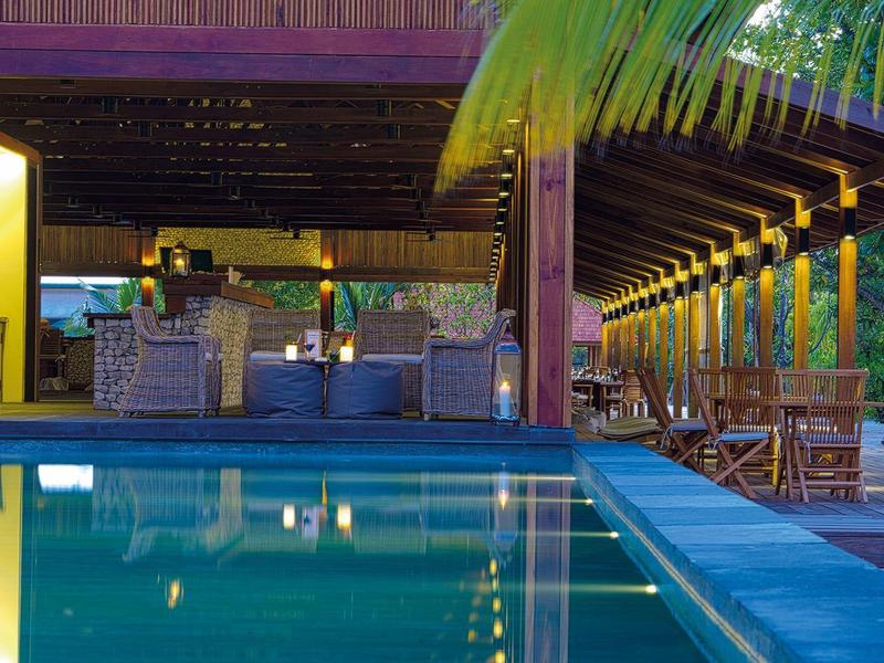 Abendliche Poolbar mit Sitzgelegenheiten und warmem Licht in einem Hotelresort.