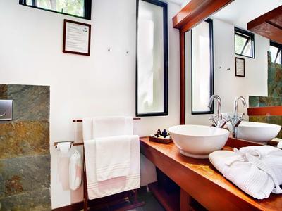 Helles Badezimmer mit weißen Handtüchern, zwei runden Waschbecken und großem Spiegel.