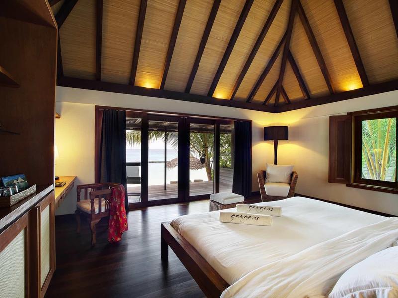 Gemütliches Schlafzimmer mit dunklem Holzboden, großen Fenstern und warmem Deckenlicht.