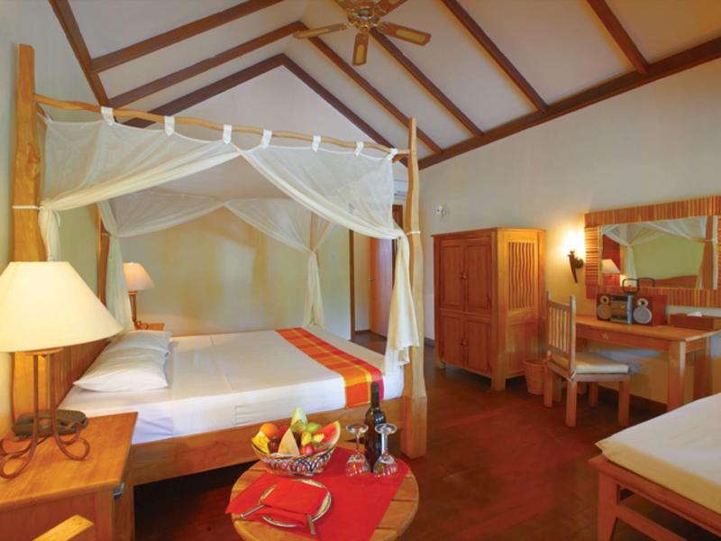 Gemütliches Schlafzimmer mit Himmelbett, Holzmöbeln, großem Spiegel und warmem Licht.