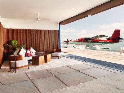 Moderne Lounge mit Holzvertäfelung und Blick auf Wasserflugzeug und Meer.