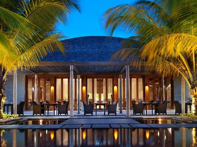 Beleuchtetes Resort mit Pool und Palmen bei Nacht unter klarem Himmel.