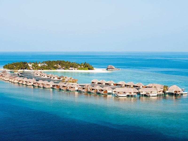 Inselresort mit über Wasser gebauten Bungalows im türkisfarbenen Meer unter klarem Himmel