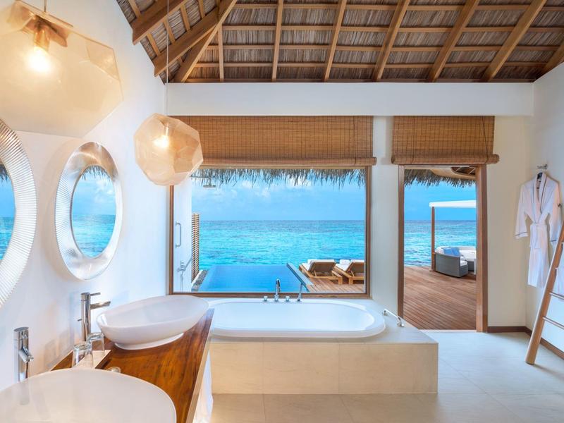 Modernes Badezimmer mit Dach aus Palmwedeln und Blick auf das Meer