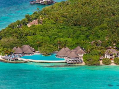 Luxusní letovisko s bazénem a pláží obklopené hustou zelení a tyrkysovou vodou.