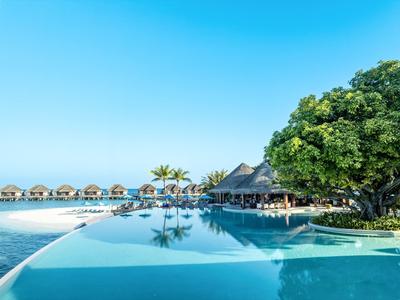 Infinity-Pool mit Blick auf das Meer und Strandhütten unter klarem Himmel