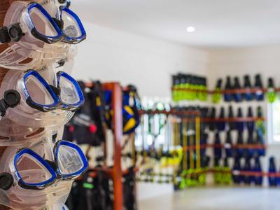 Plusieurs masques de plongée suspendus dans un magasin de plongée avec équipement en arrière-plan.