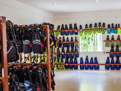 Salle lumineuse avec des étagères et des murs remplis d'équipements de plongée et de bouteilles.