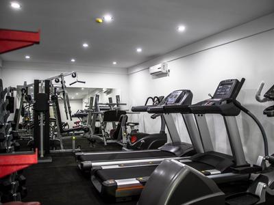 Vue intérieure d'une salle de sport moderne avec des tapis roulants, des poids et d'autres équipements d'exercice.