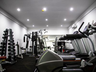 Salle de sport moderne avec tapis roulants, haltères et appareils de musculation dans un hôtel.