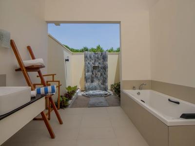 Modernes Badezimmer mit Waschbecken, Badewanne und Wasserfall-Deko im Außenbereich.