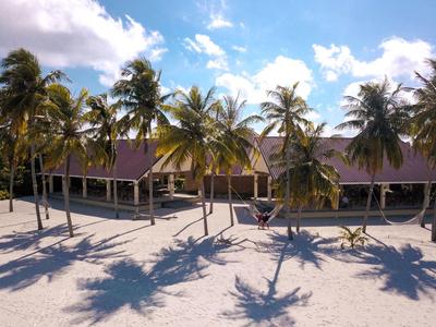 Strandresort mit Palmen und Bungalows bei sonnigem Himmel.