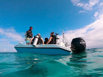 Groupe de personnes sur un petit bateau à moteur dans une mer bleue claire sous un ciel ensoleillé.
