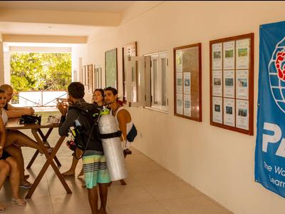 Des plongeurs sont devant une école de plongée avec une bannière PADI en train de parler au personnel.