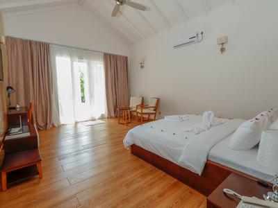 Helles Hotelzimmer mit Holzboden, großem Bett und Sitzbereich am Fenster.