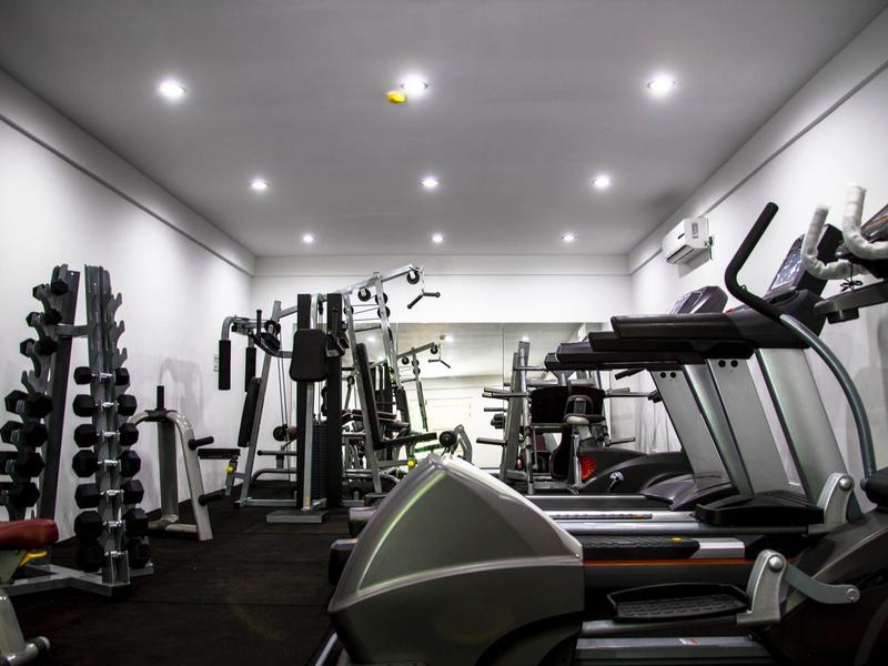 Moderner Fitnessraum mit Hanteln, Laufbändern und Kraftgeräten in hellem Raum