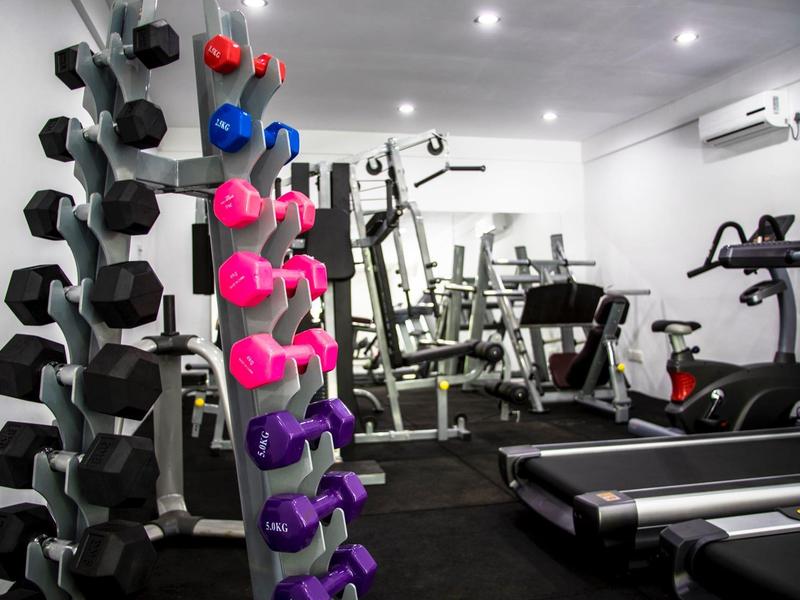 Moderner Fitnessraum mit Hanteln, Laufbändern und Trainingsgeräten in einem Hotel.