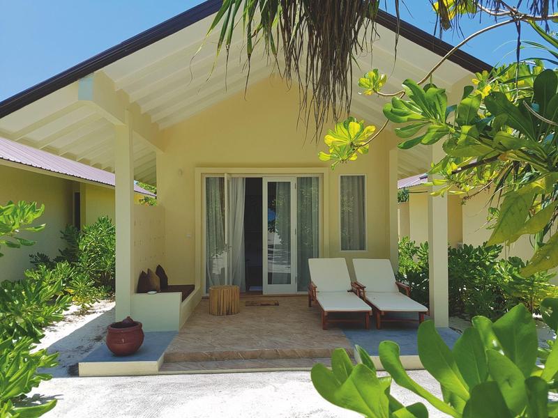 Gemütliche Veranda mit zwei Liegestühlen und Pflanzen vor einem Hotelbungalow.