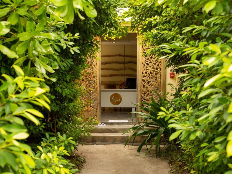 Grüner Gartenweg führt zu einem dekorativen Hauseingang mit geschnitzten Holztüren.