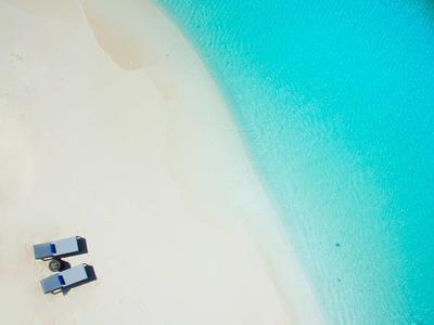 Due sdraio su sabbia bianca accanto ad acqua turchese trasparente sulla spiaggia