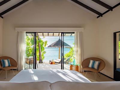 Widok z pokoju hotelowego na taras z widokiem na morze i leżaki.