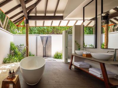 Nowoczesna łazienka z wolnostojącą wanną i dużą szklaną ścianą otwierającą się na taras ogrodowy.