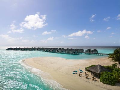 Plaża z hamakami, parasolami i bungalowami nad wodą pod czystym niebem