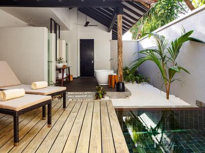 Nowoczesny taras z drewnianą podłogą, leżakami, basenem i tropikalną roślinnością.