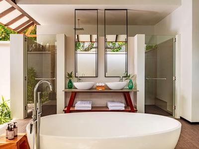 Nowoczesna łazienka z wolnostojącą wanną, podwójnymi umywalkami i otwartym designem z dużą ilością naturalnego światła.