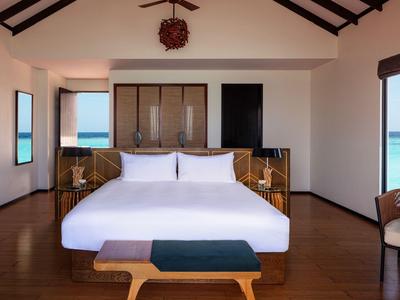 Nowoczesny pokój hotelowy z łóżkiem, drewnianymi meblami i widokiem na morze przez okna.