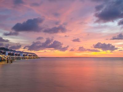 Spokojne wybrzeże z domami nad wodą i kolorowym zachodem słońca.