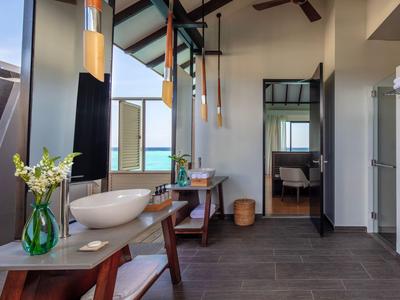 Nowoczesna łazienka hotelowa z dużymi oknami, podwójnymi umywalkami i widokiem na morze.