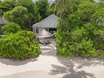 Tropikalny kurort nad morzem z piaszczystą plażą, zielonymi drzewami i chatką na plaży.